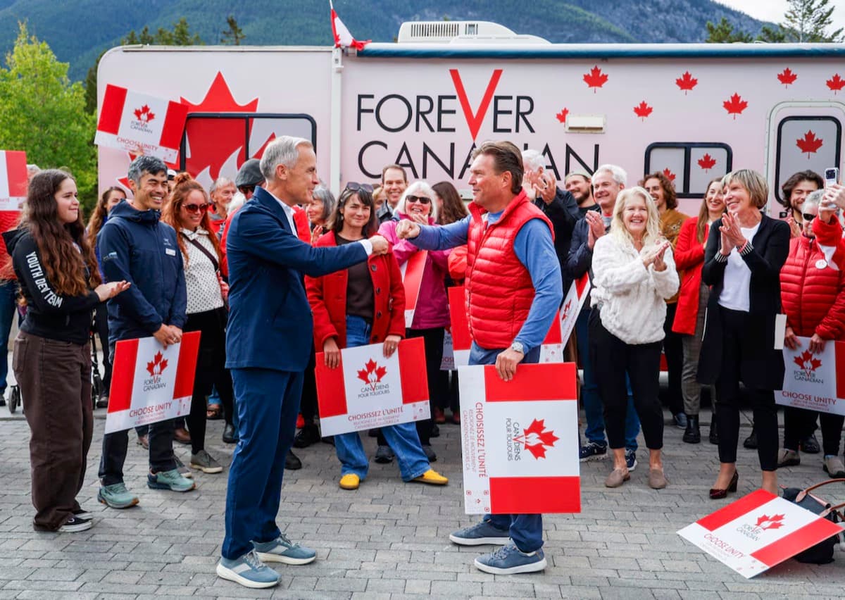 Thomas Lukaszuk shaking hands with Prime Minister Mark Carney in front of the Unity Bus, surrounded by Forever Canadian volunteers